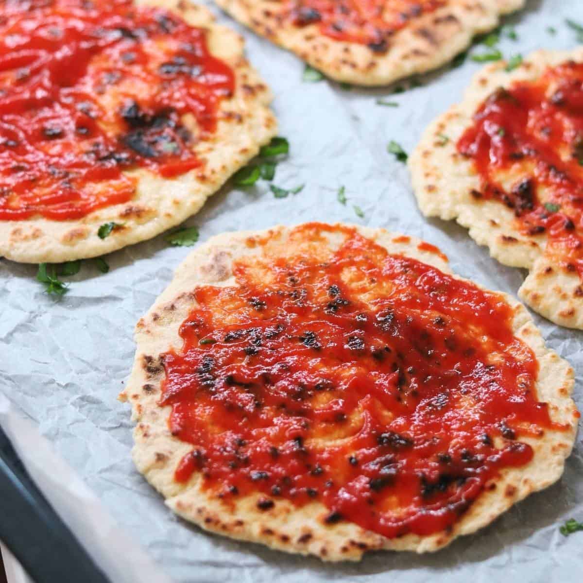 spreading passata on naans.