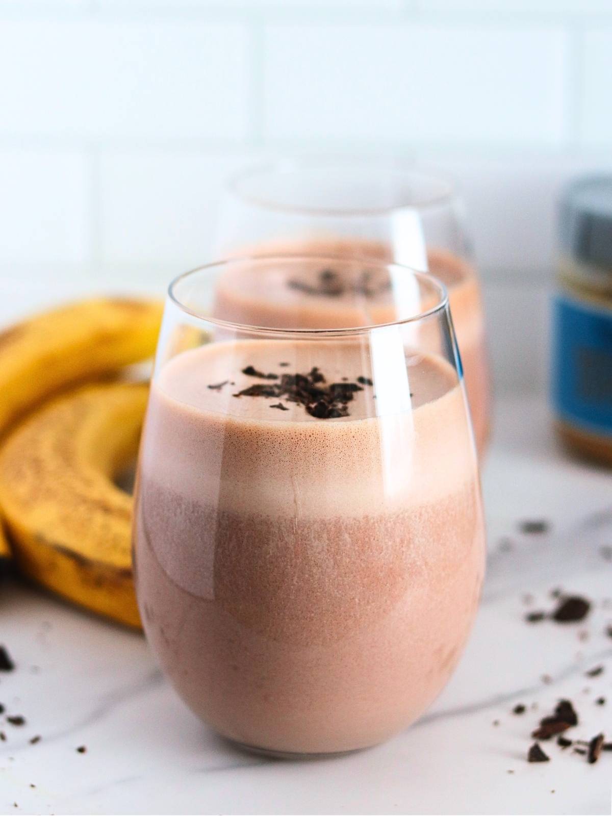 glasses of chocolate protein shake on a table. with ingredients on a background.