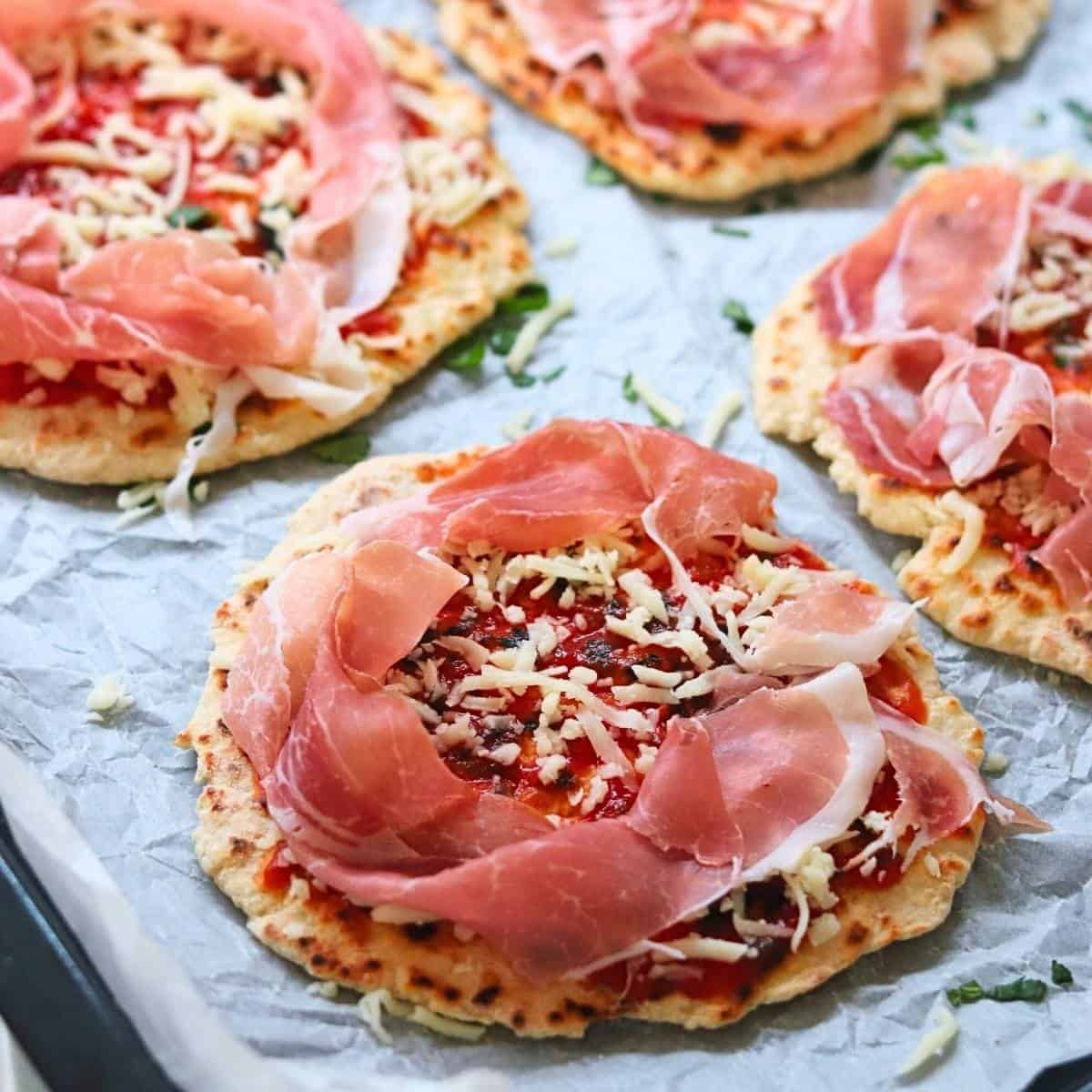sprinkling naans with grated mozarella and prosciutto.