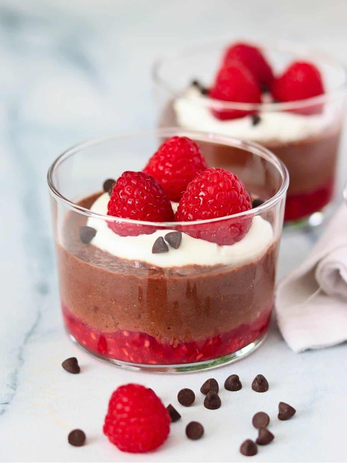 A glass of chocolate raspberry chia pudding with a healthy presentation.